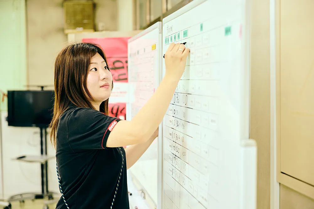 女性がホワイトボードに文字を書いている様子