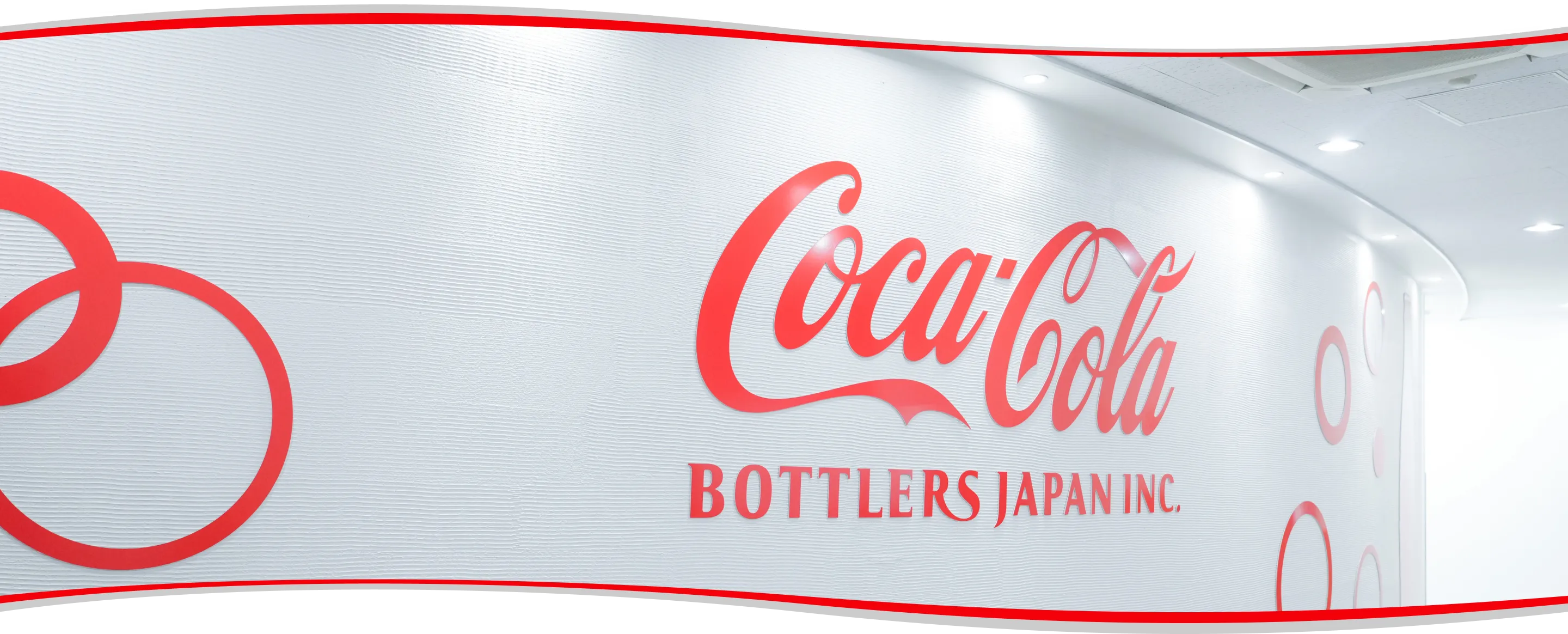 コカ･コーラ ボトラーズジャパンのロゴが描かれた壁